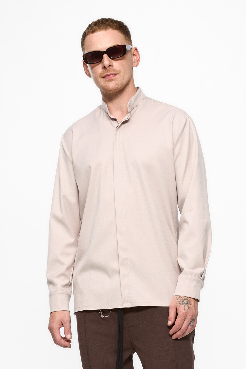 Man wearing a light-colored shirt and sunglasses on a white background