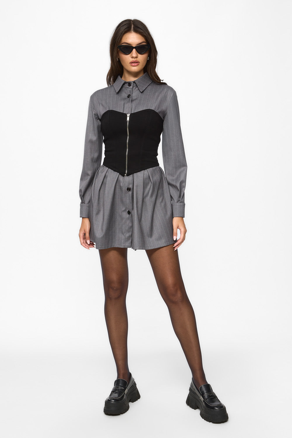 Woman wearing a gray shirt dress over a black corset on a white background