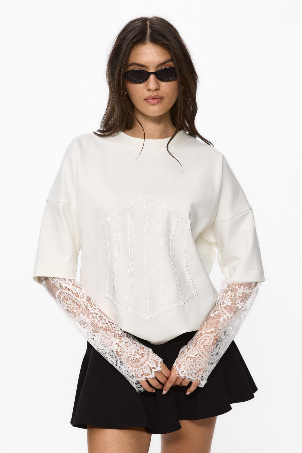 Woman wearing a white blouse with lace sleeves and a black skirt on a white background