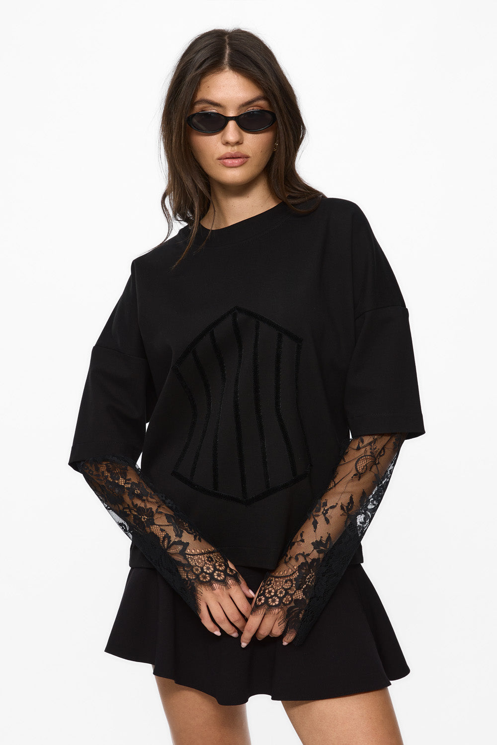 Woman wearing a black outfit with lace sleeves on a white background. Venice T-shirt for women from Atelier Hamza.