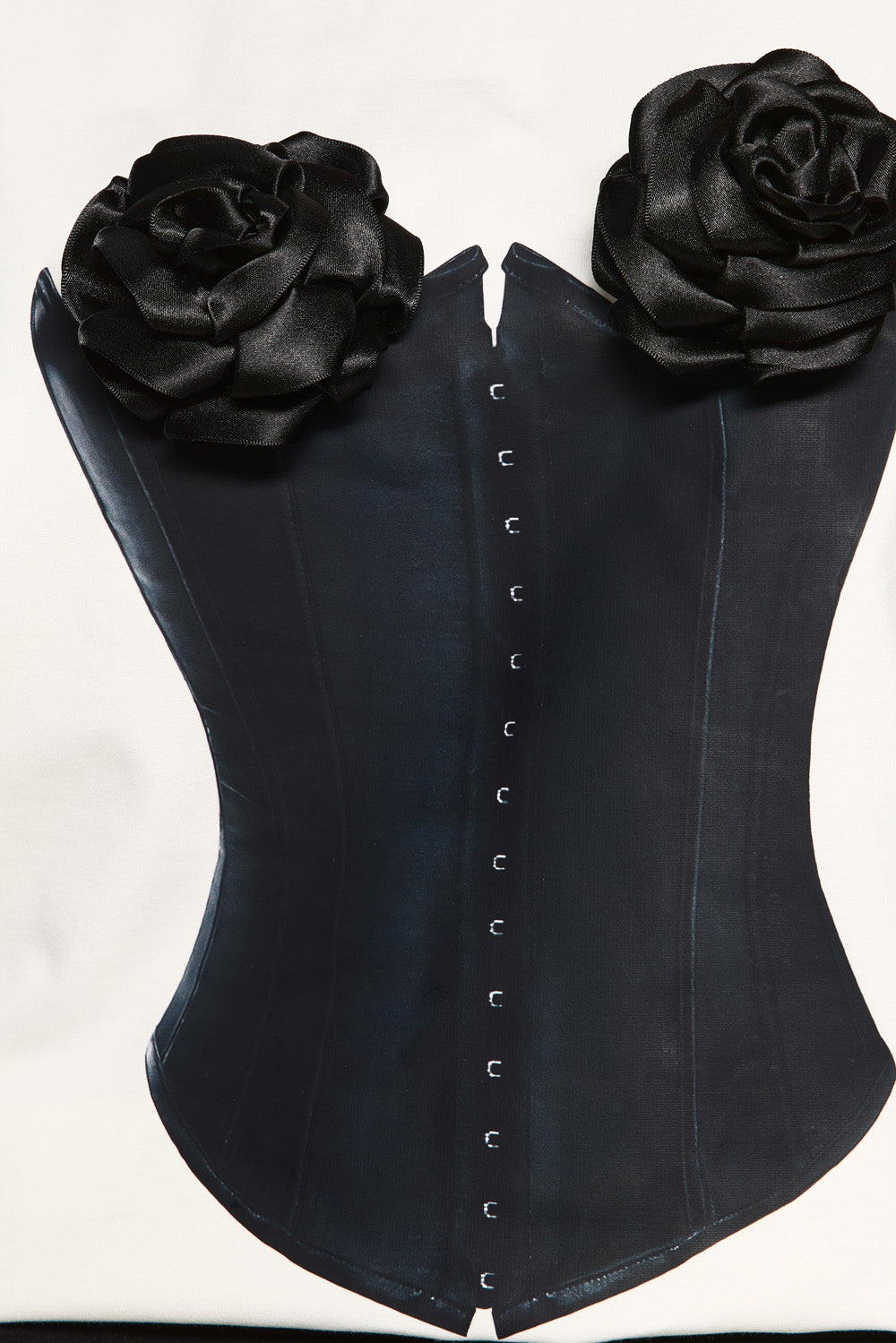 Black corset with floral embellishments on a white background