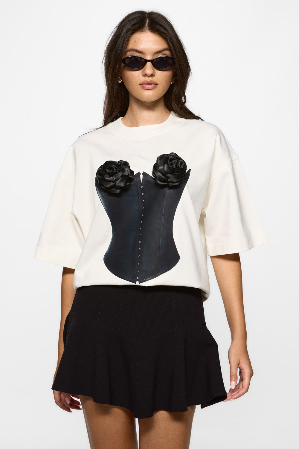 Woman wearing a white top with black corset design and black skirt on a white background