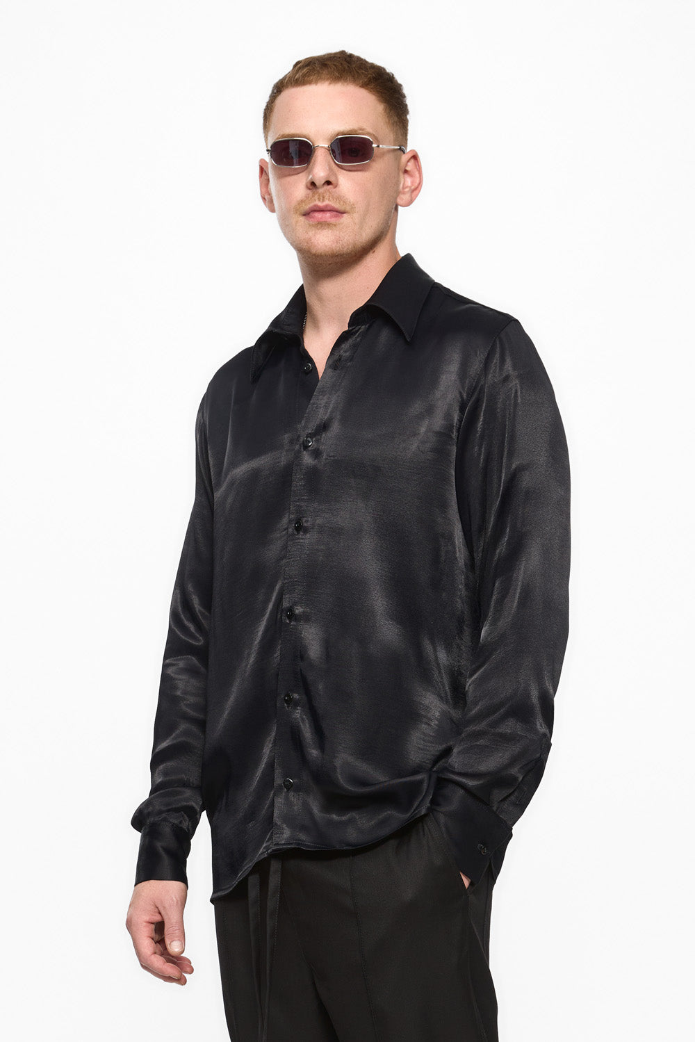 Man wearing a black satin shirt and sunglasses on a white background