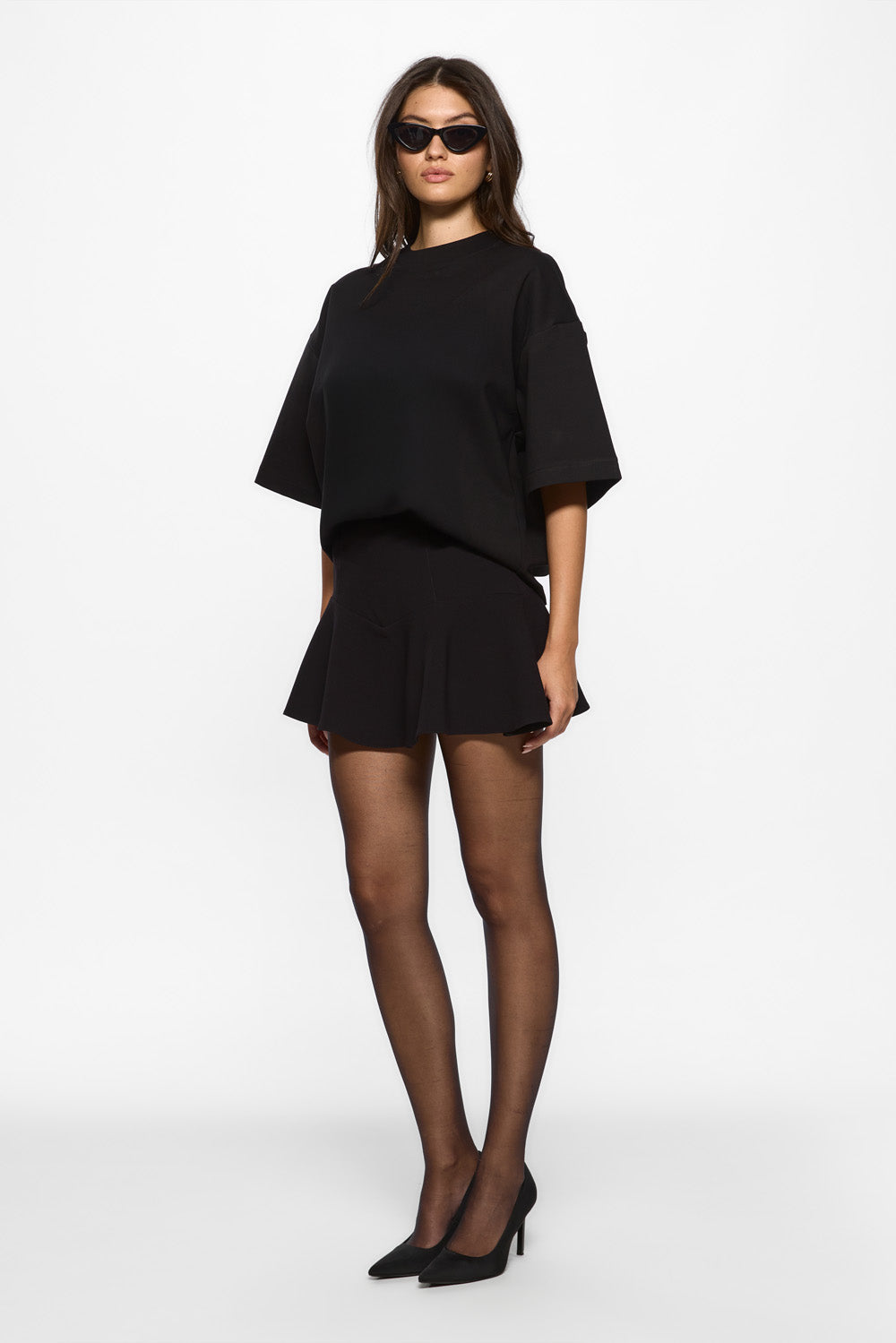 Woman wearing a black outfit with sunglasses on a white background