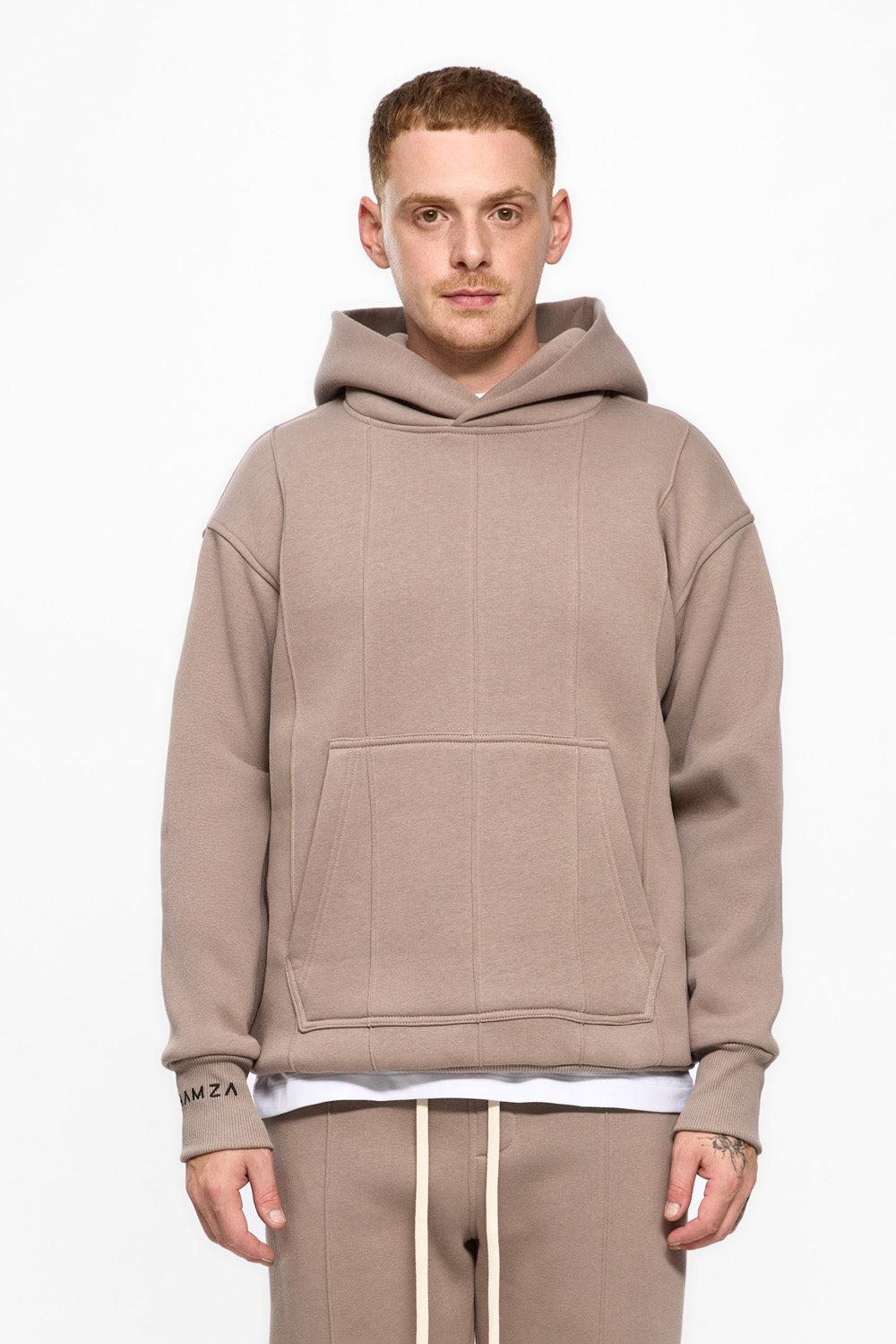 Man wearing a beige hoodie and pants on a white background