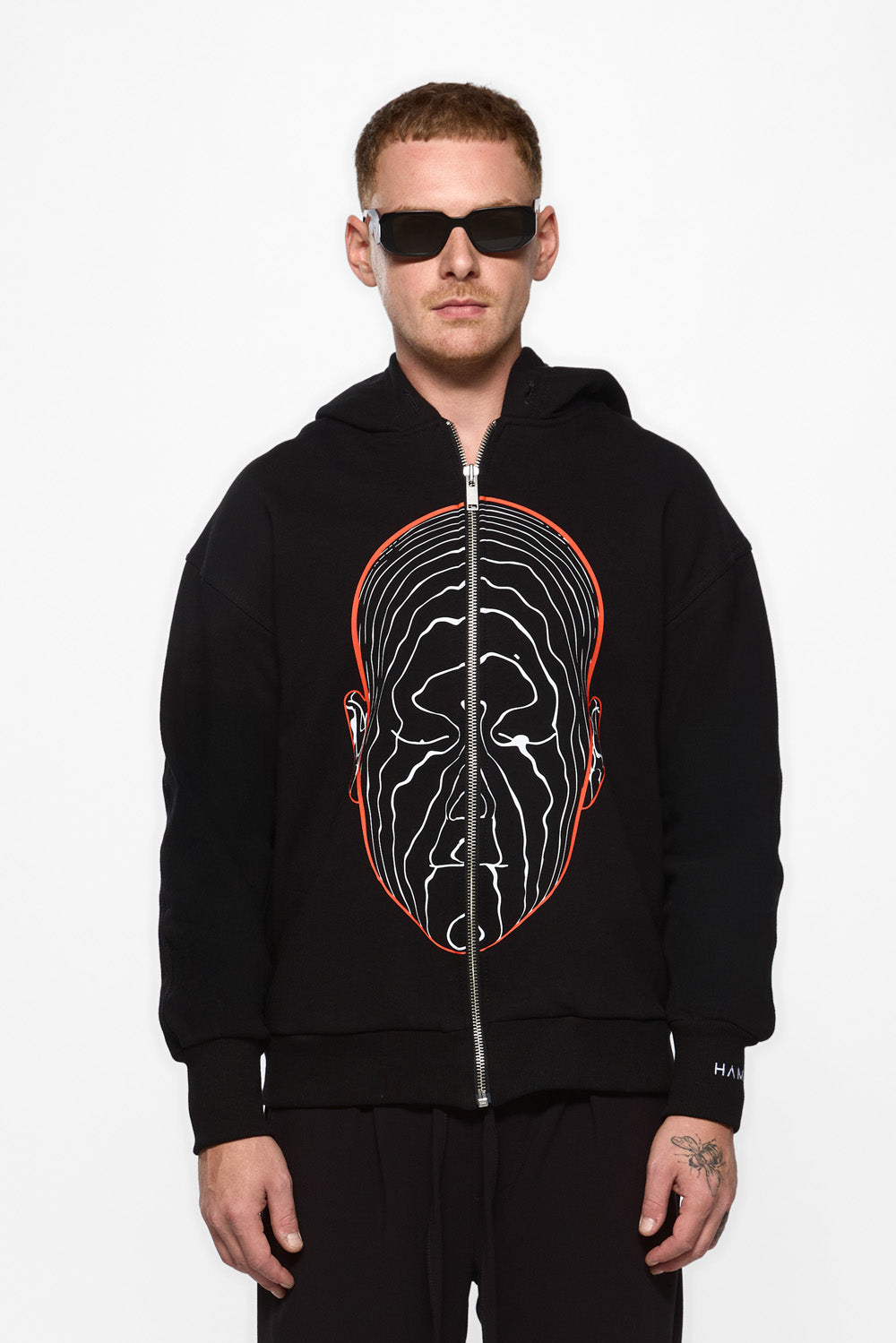 Person wearing a black hoodie with a unique design on a white background