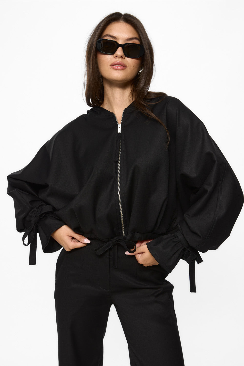 Person wearing a black outfit with a jacket and pants on a white background