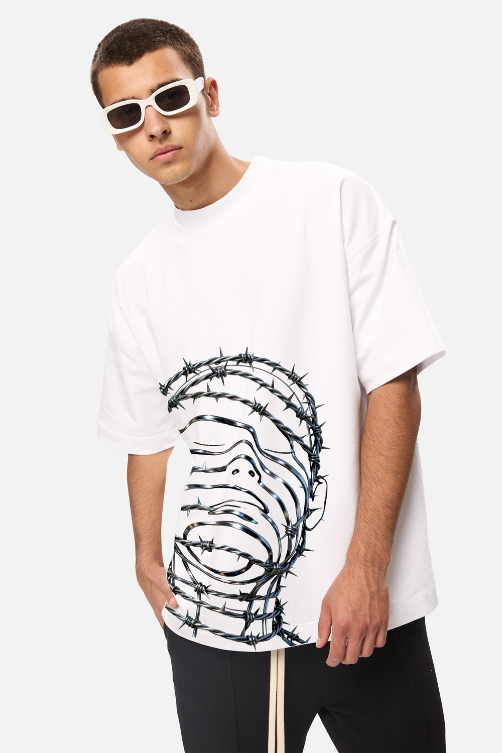 Model purtând tricoul oversized alb Barbed Wire Head pentru bărbați, vedere frontală din unghi, evidențiind imprimeul grafic