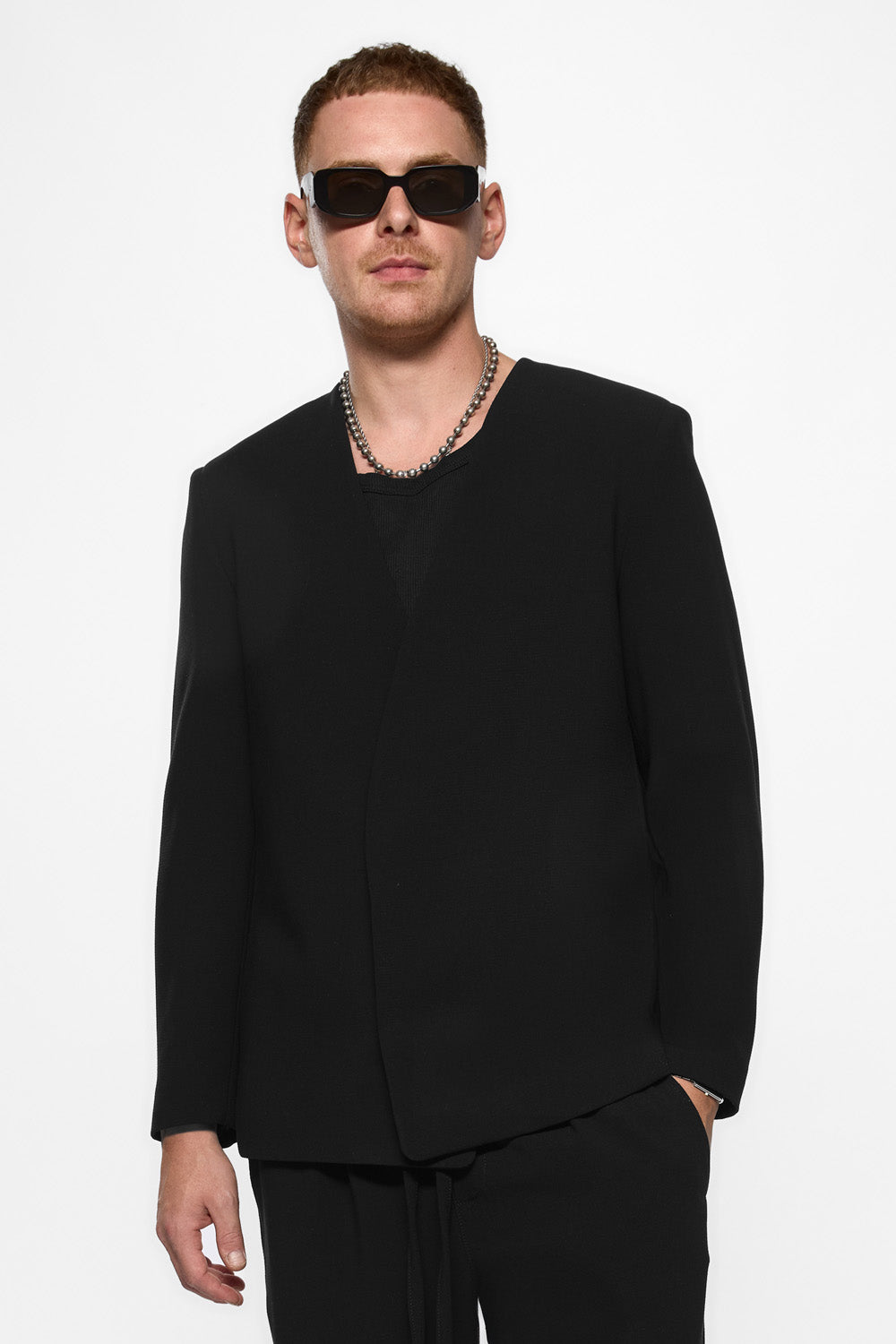 Man wearing a black outfit with sunglasses on a white background