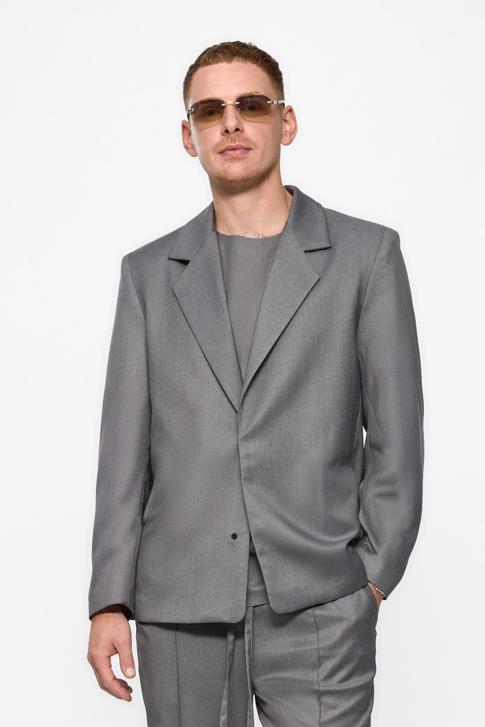 Man wearing a gray suit and sunglasses on a white background