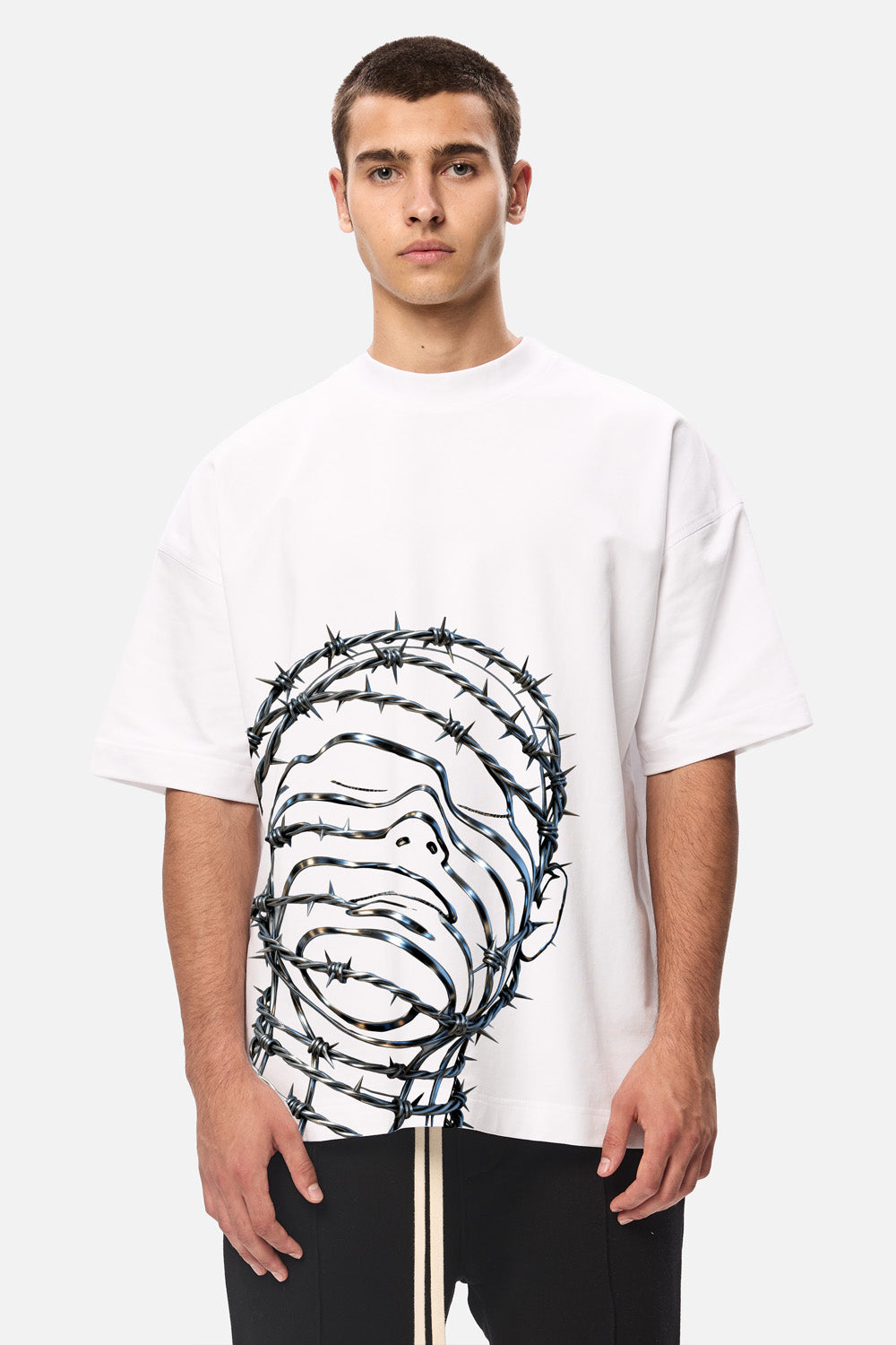 Model purtând tricoul oversized alb Barbed Wire Head pentru bărbați, vedere din față, cu imprimeu grafic din sârmă ghimpată