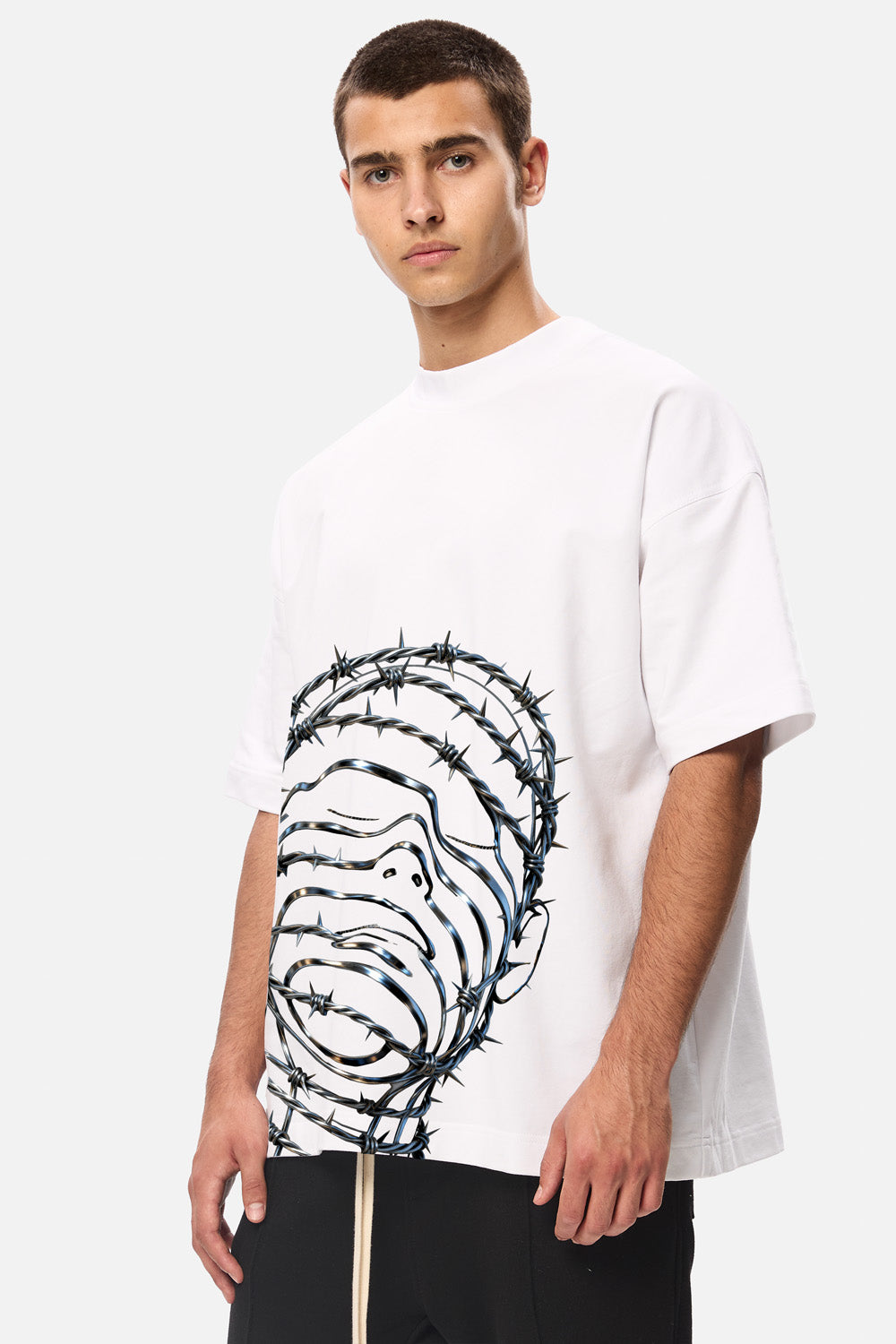 Model purtând tricoul oversized alb Barbed Wire Head pentru bărbați, vedere frontală din unghi, evidențiind imprimeul grafic