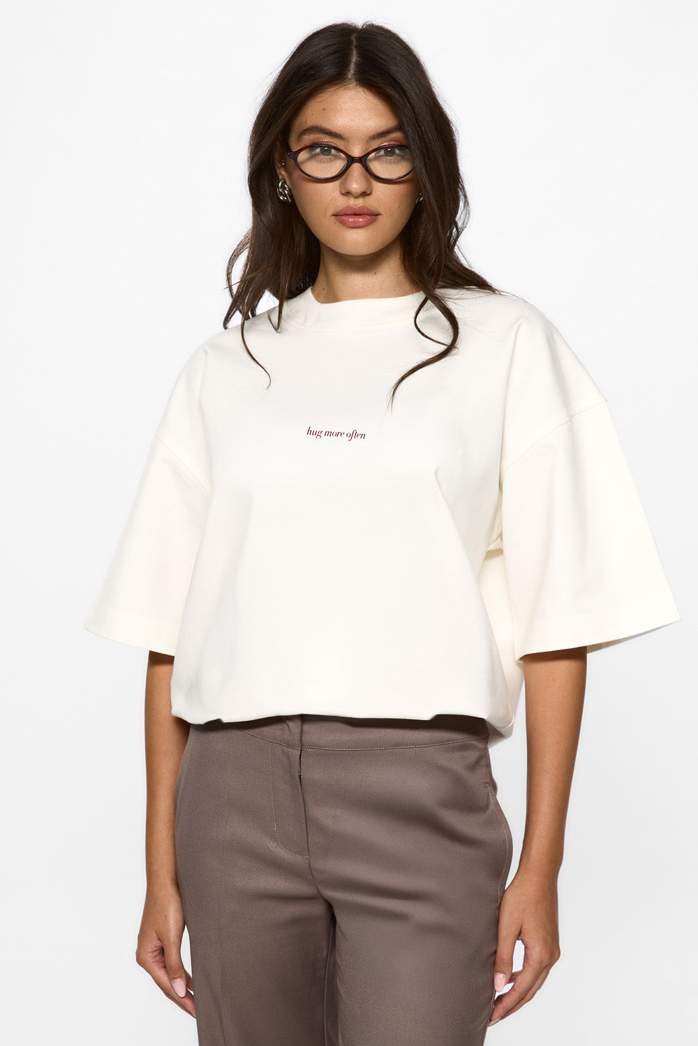 Vedere frontală din unghi a unui model purtând tricoul Off-White Burgundy Hug pentru femei, evidențiind croiala oversized și imprimeul frontal