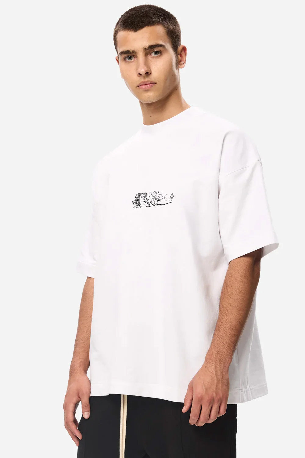 Angled front view of a model wearing the Line Art white boxy T-shirt for men with a small line-art chest print