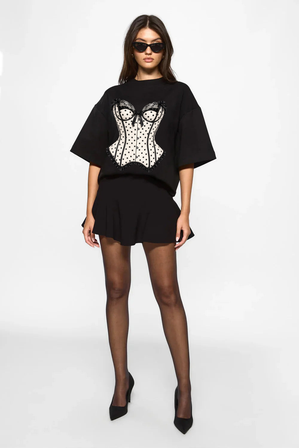 Vedere full-body din față a unui model purtând tricoul oversized negru Polka Dots Corset pentru femei, cu imprimeu tip corset cu buline.