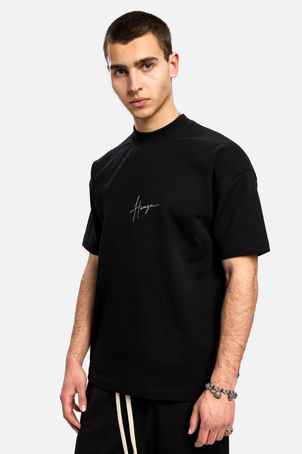 Vedere frontală din unghi a unui model purtând tricoul boxy negru They Will Ignore You pentru bărbați